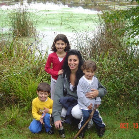 Founder Joanne with her three children in a natural setting with water and greenery.